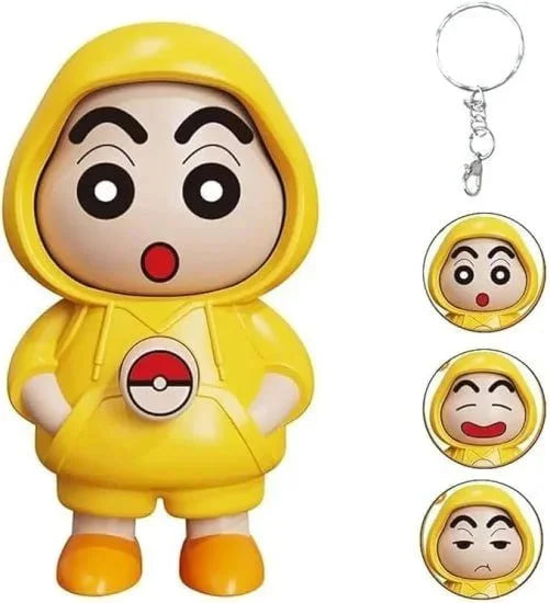 A toy figure of the character Shinchan wearing a yellow hoodie with a Pokeball design, displayed next to a metal keychain ring and three interchangeable face plates showing different expressions.