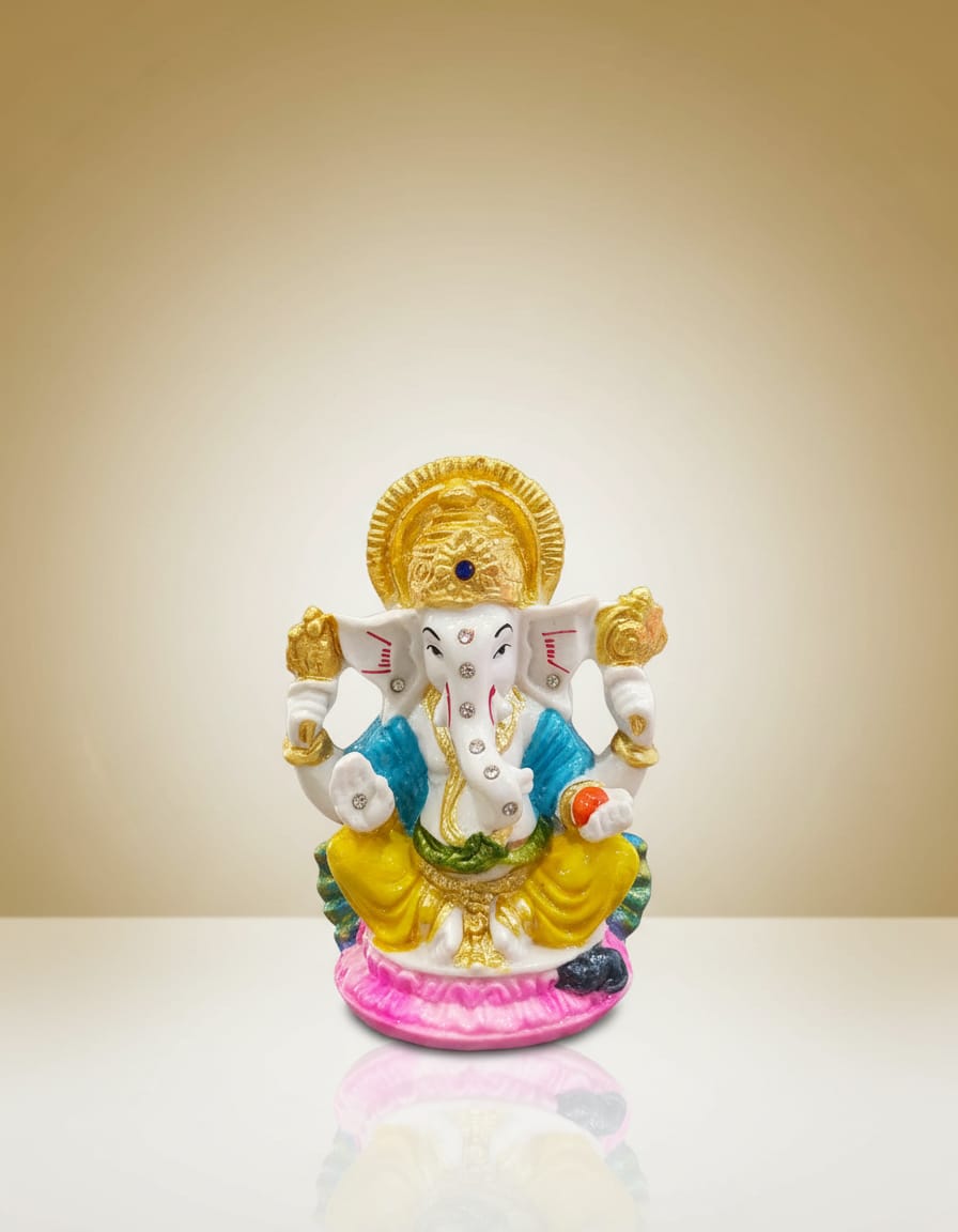 A beautifully detailed Lord Ganesha idol featuring a white body, golden crown, blue and yellow garments, seated peacefully on a bright pink lotus base.