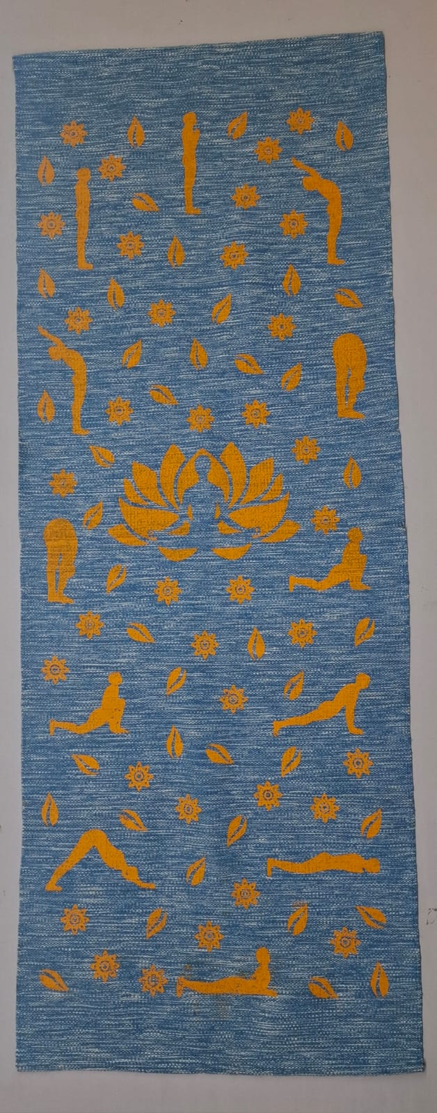 A blue eco-friendly cotton yoga mat printed with yellow Surya Namaskar poses.