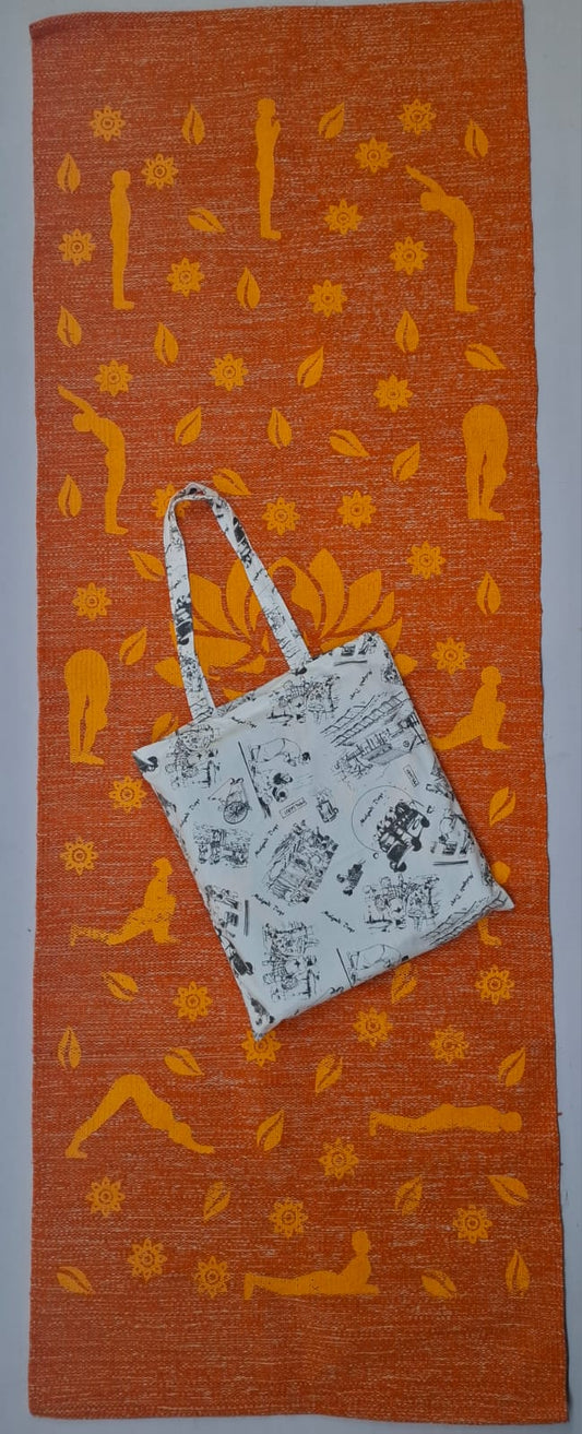 An orange eco-friendly cotton yoga mat printed with yellow Surya Namaskar poses, shown with a matching printed light-colored tote bag resting on top.
